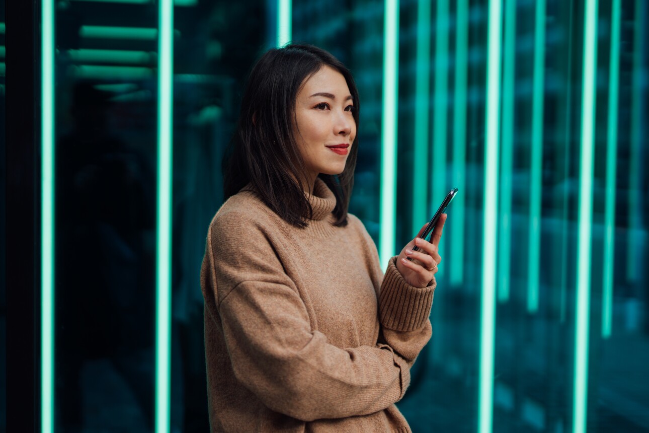 Young woman using mobile phone against futuristic holographic background