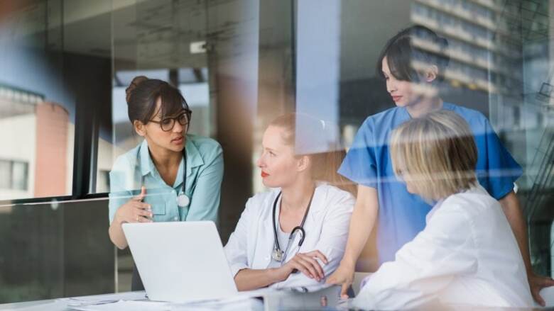 doctors and nurses discussing information on a laptop