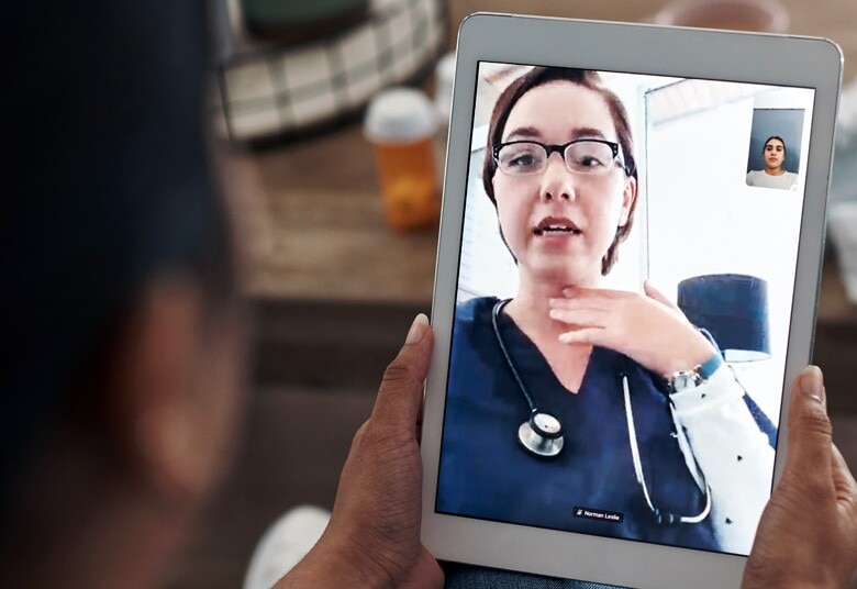 person holding tablet while having a telehealth visit with their doctor