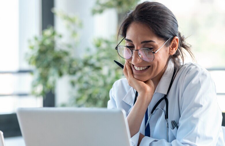 Smiling female doctor working with her laptop in the consultation.