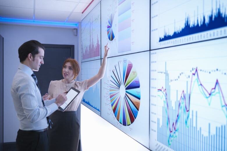 Business colleagues discussing graphs on screen in meeting room