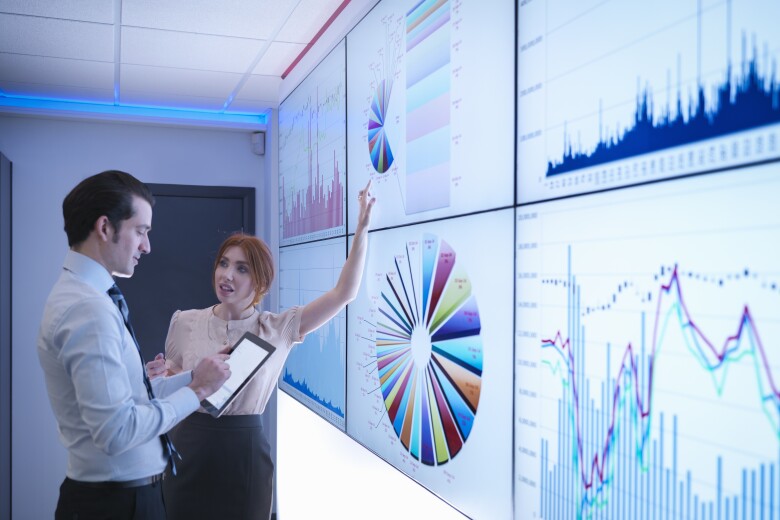 Business colleagues discussing graphs on screen in meeting room