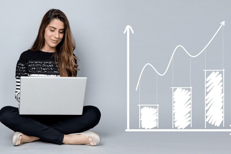 woman sitting on the floor with a laptop next to an illustration of a graph
