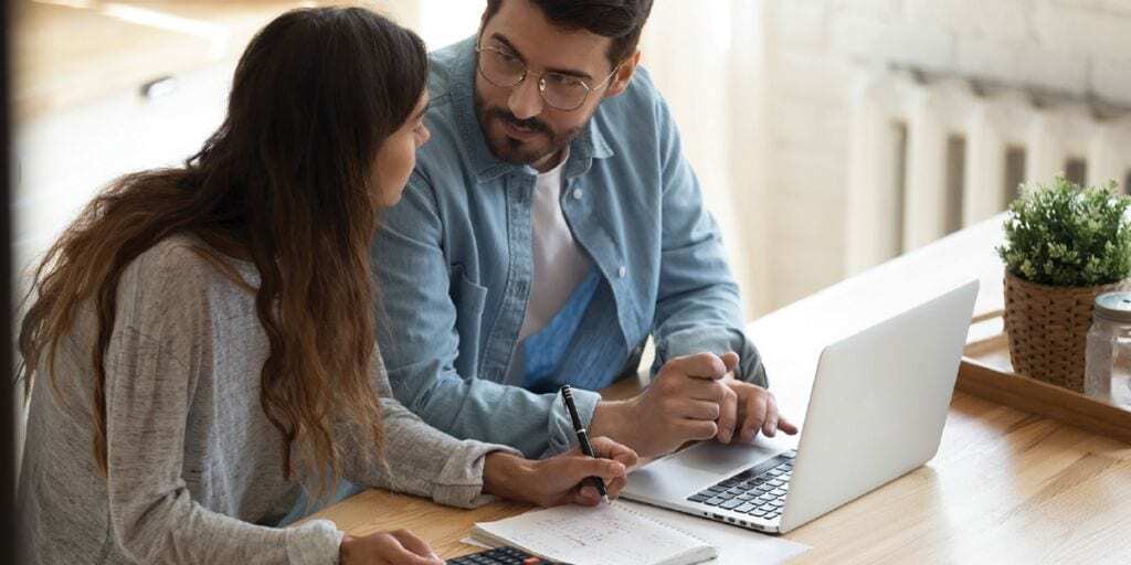 couple discussing their finances while working on a laptop