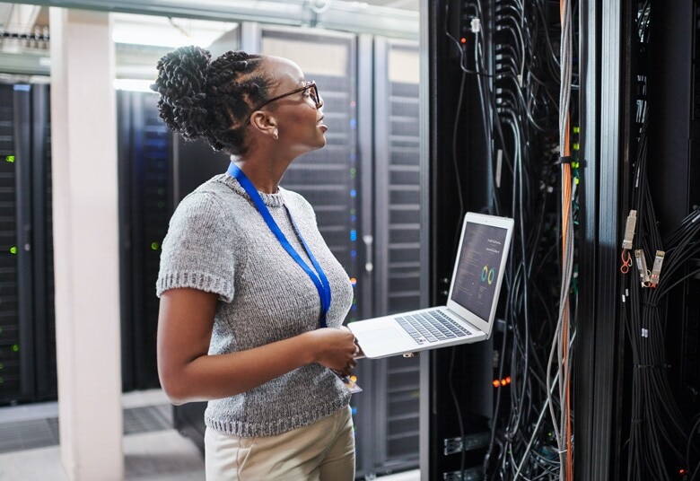 network engineer working on her laptop in a server room