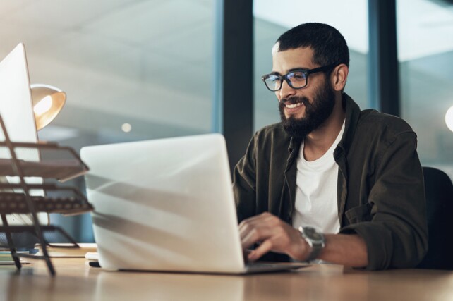 young professional smiling working on laptop in an office