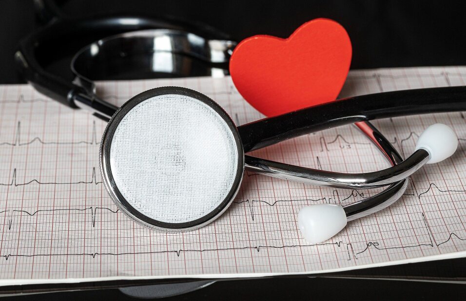 stethoscope and red heart pin placed on an EKG reading