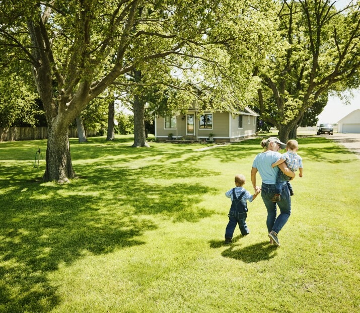 Grandmother walking with grandsons through front yard