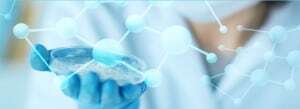 a lab worker's gloved hand holding a petri dish