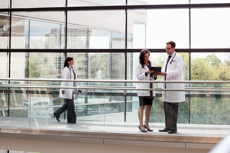 doctors reviewing information on a tablet in a hospital hallway