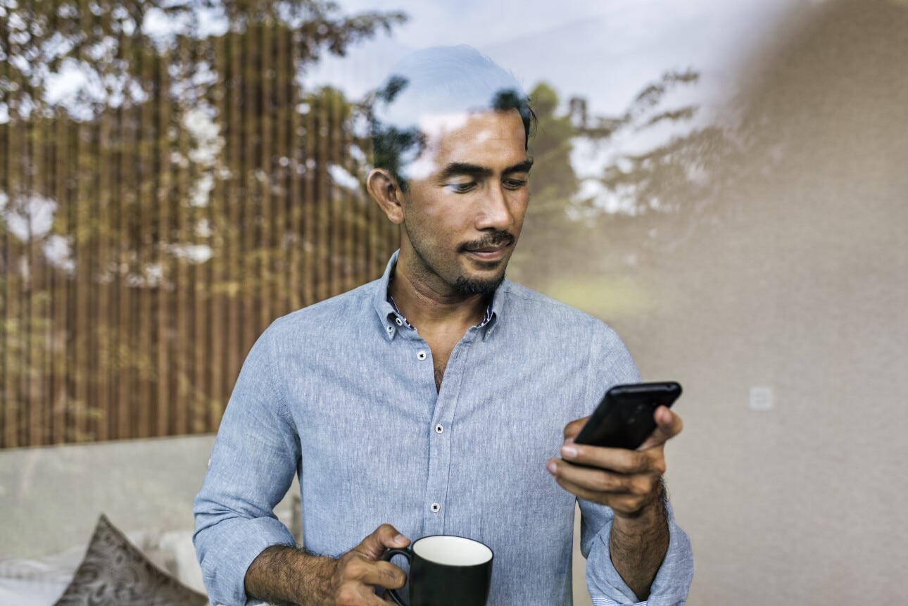 Asian businessman working from home,  using smartphone and drinking coffee