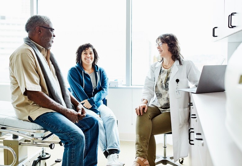 doctor having a conversation with patient and his wife in an exam room