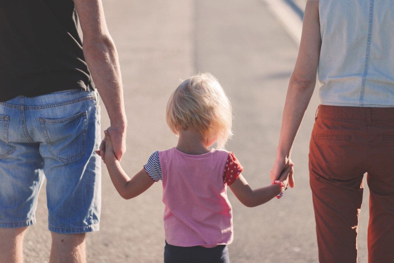 parents holding young child's hand