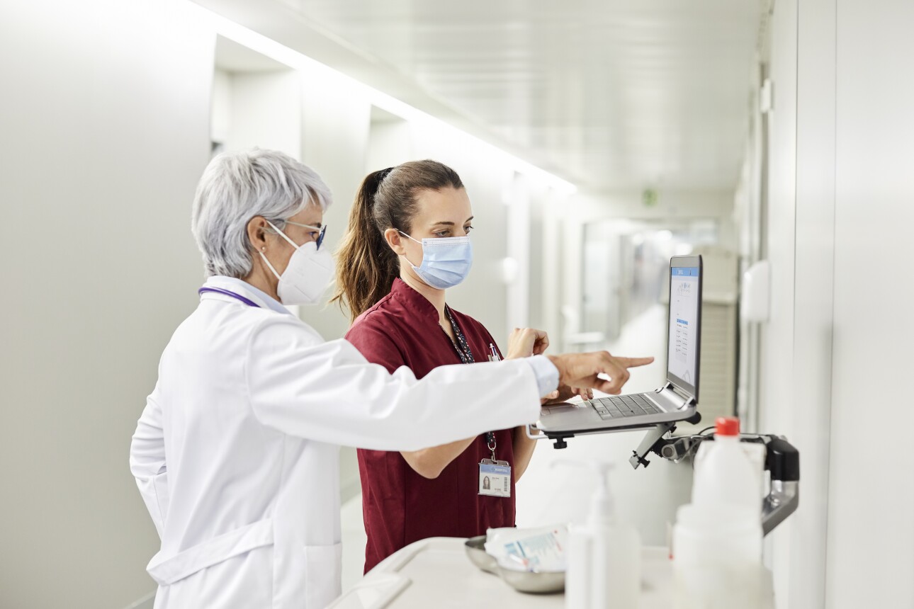 Doctor pointing at laptop by nurse in hospital