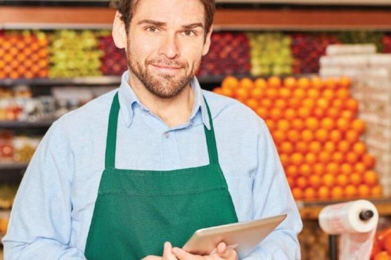 manager of a grocery store standing in the produce section