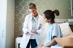 doctor looking at tablet with patient in a hospital room