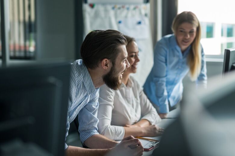 Three office employees sitting at desk smiling