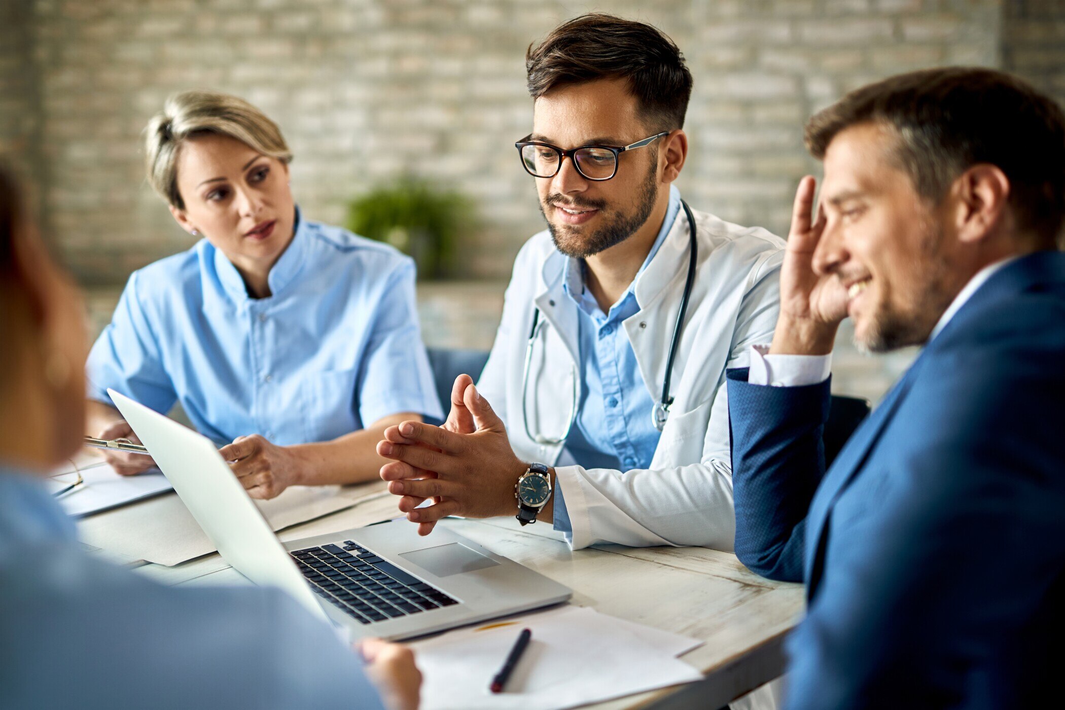 Group of healthcare workers and businessman using laptop while having a meeting in the office.