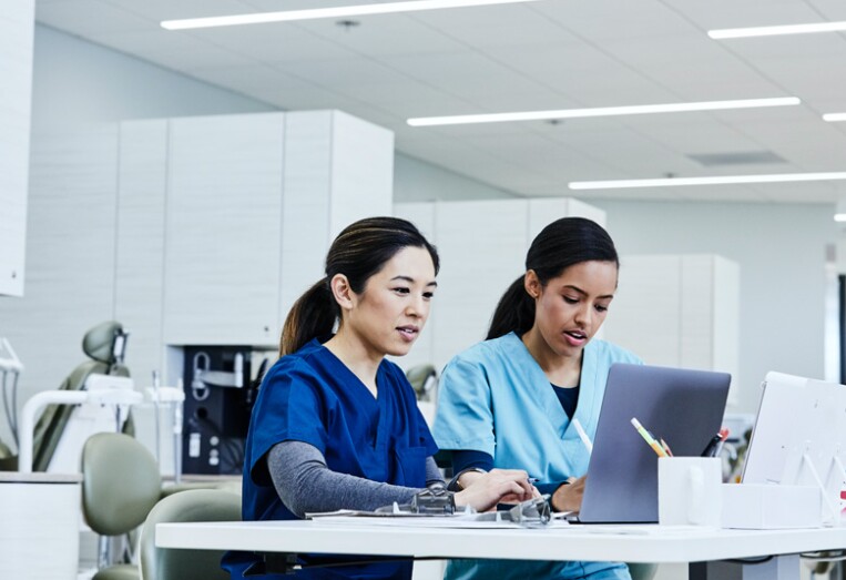 nurses updating patient records on computers at the nurse's station