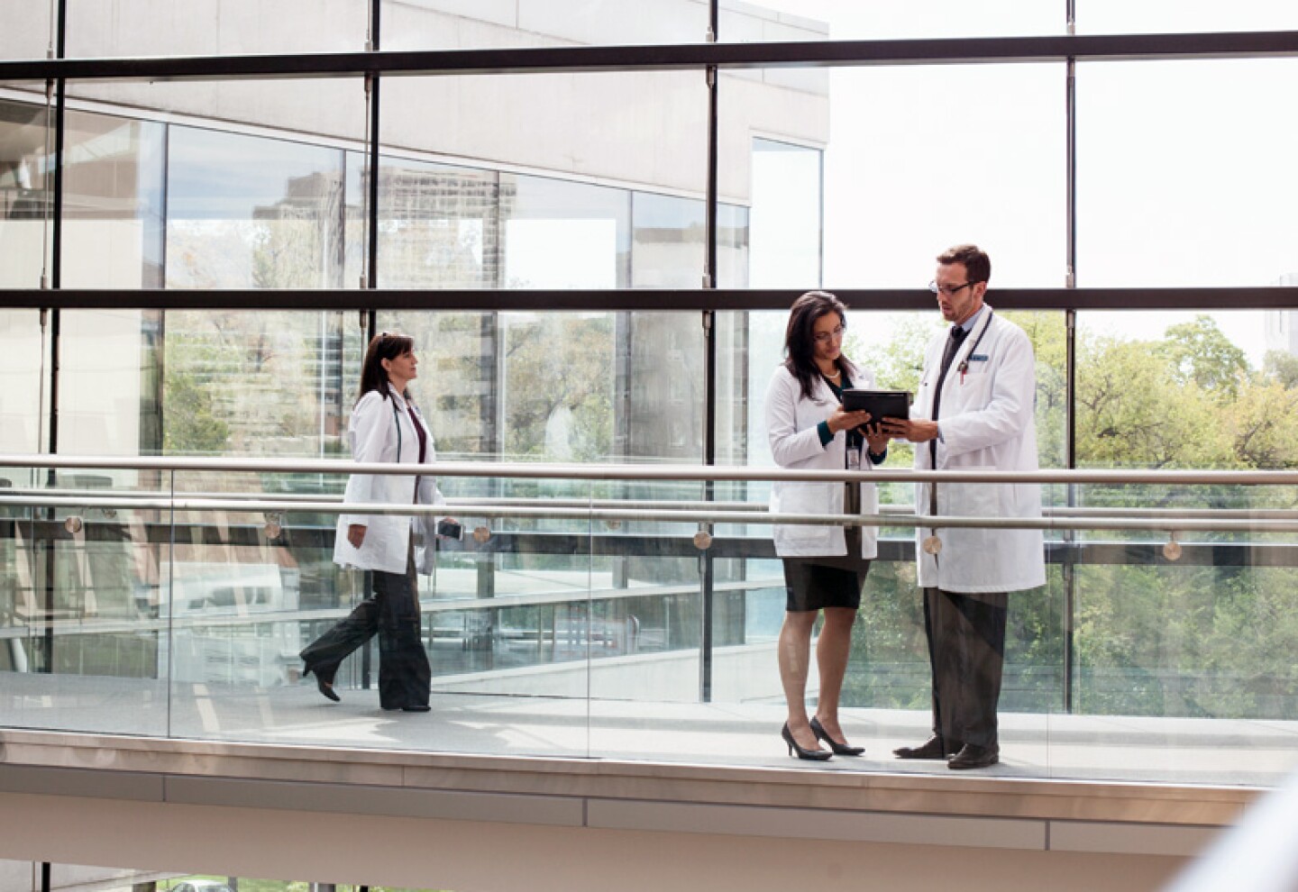 doctors reviewing information on a tablet in a hospital hallway