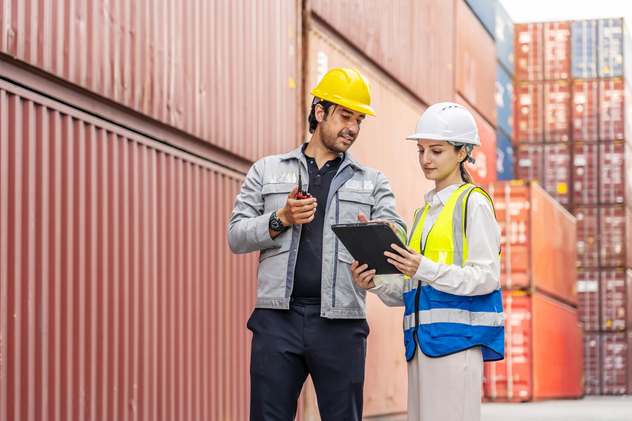 Professional logistics managers in hardhats inspecting shipping containers