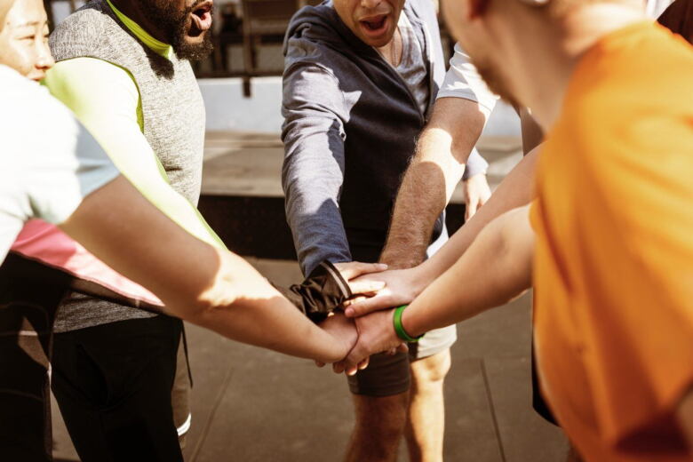 group of adults with their hands stacked in the middle showing teamwork
