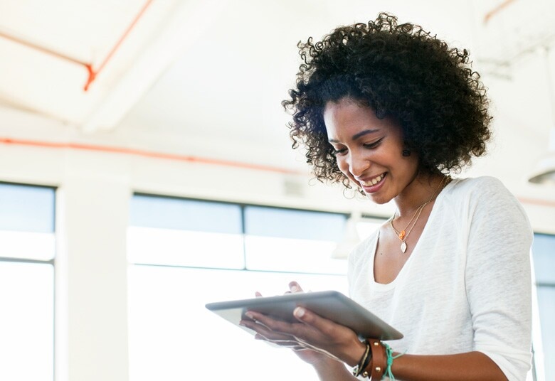 woman smiling while looking at her tablet