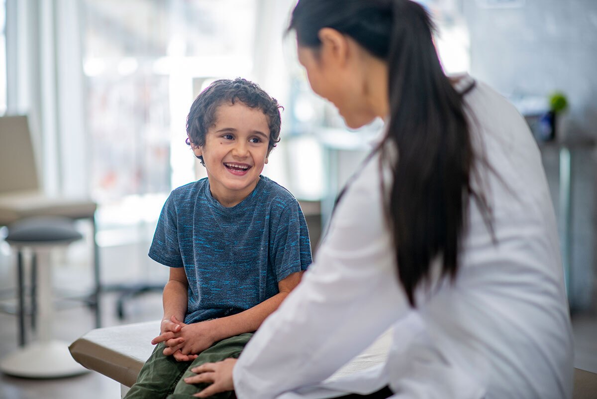 young boy laughing during a visit with his doctor