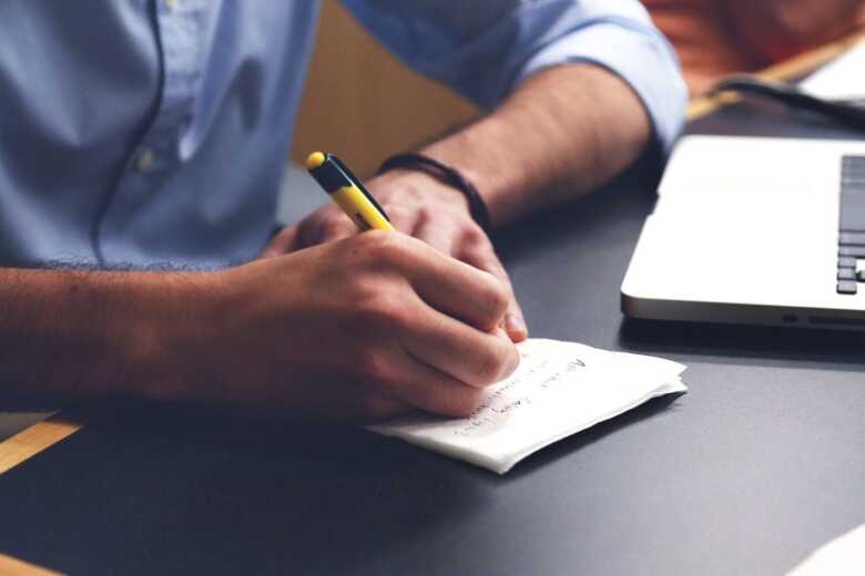 man sitting at a desk at work taking notes on paper
