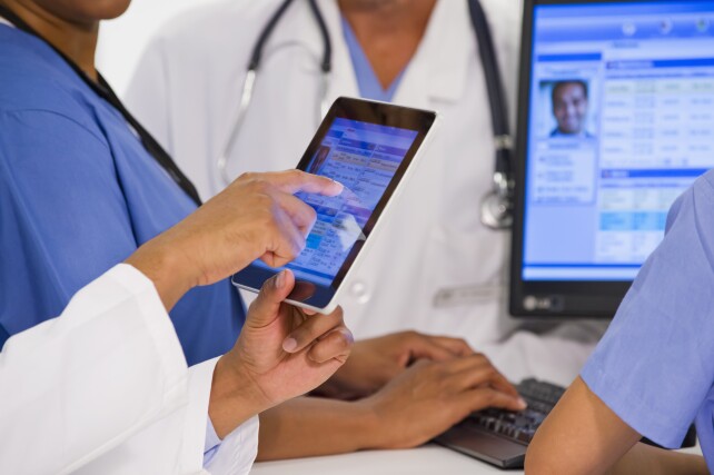 Doctors using tablet with patient records