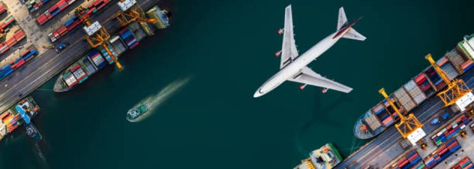 Aerial view and top view cargo plane flying above ship port in the export and import business and logistics international goods. Shipping cargo to harbor by crane