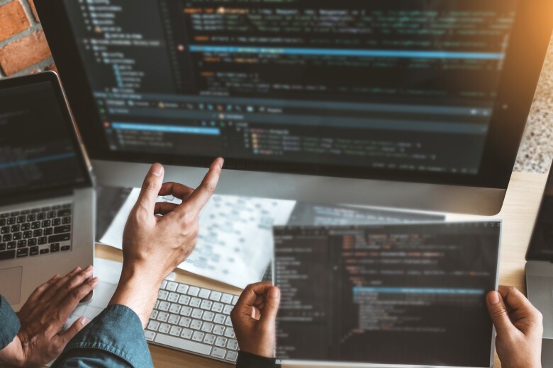 computer programmers comparing code on a large computer screen