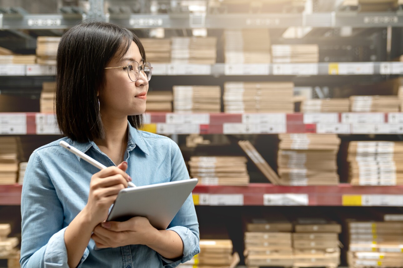 Woman in warehouse taking inventory on tablet