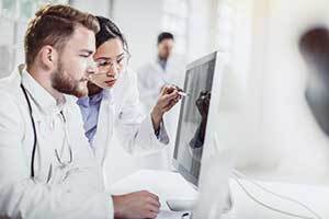 doctors in white coats studying information on a computer screen