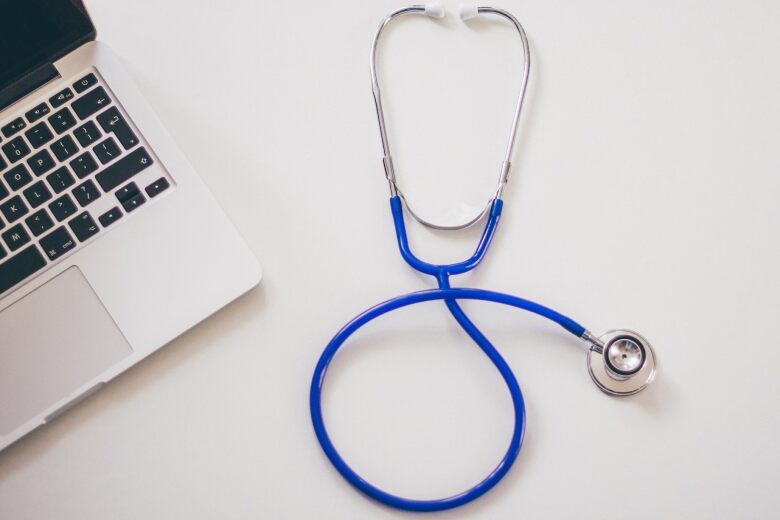 desktop with open laptop and blue stethoscope
