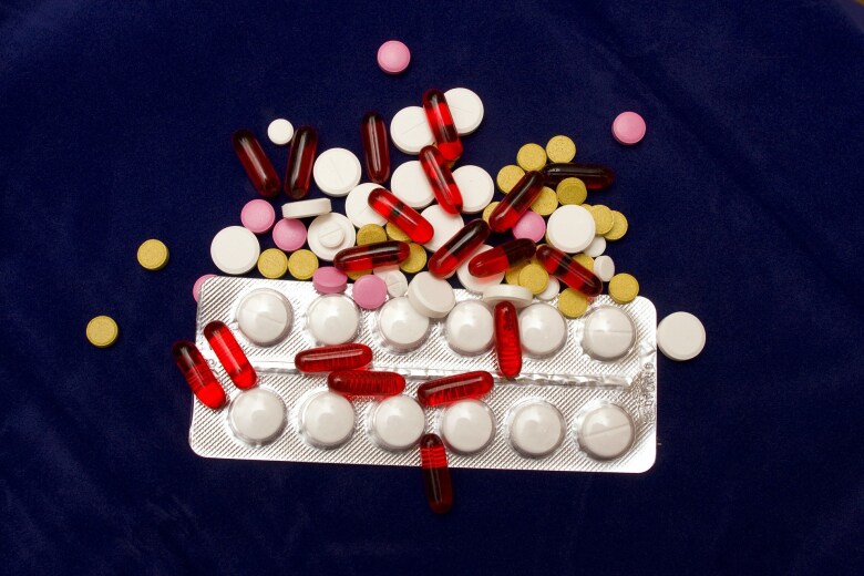 variety of pills spilled on a dark blue surface