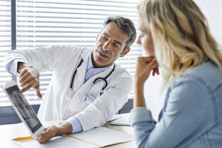 Doctor showing digital tablet to woman in hospital