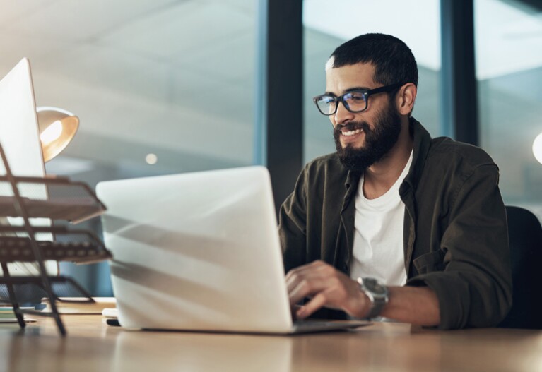 young professional smiling working on laptop in an office