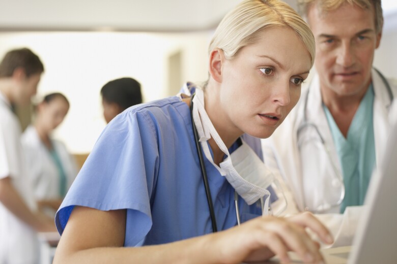 Nurse typing on computer with male doctor
