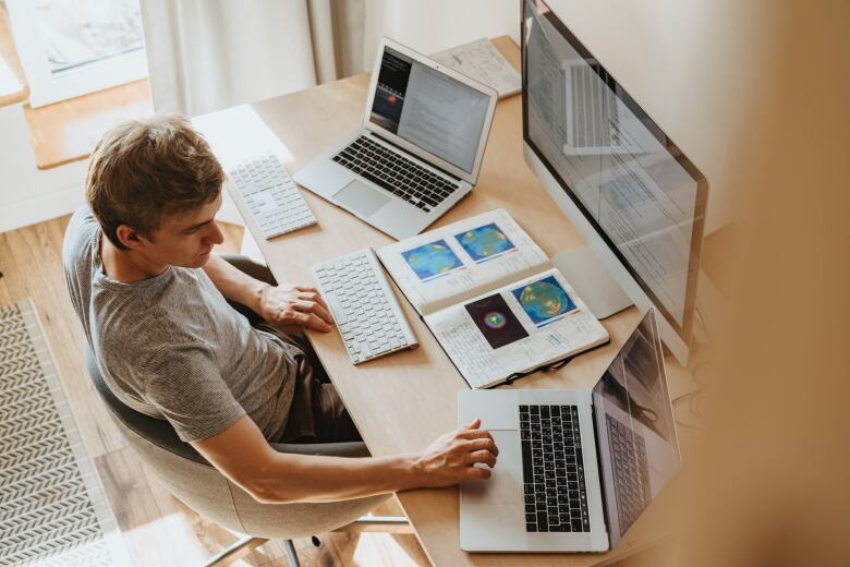 young man at a desk working on multiple computers