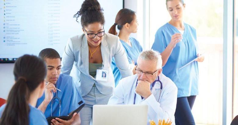 hospital administrator reviewing information on a laptop with medical staff