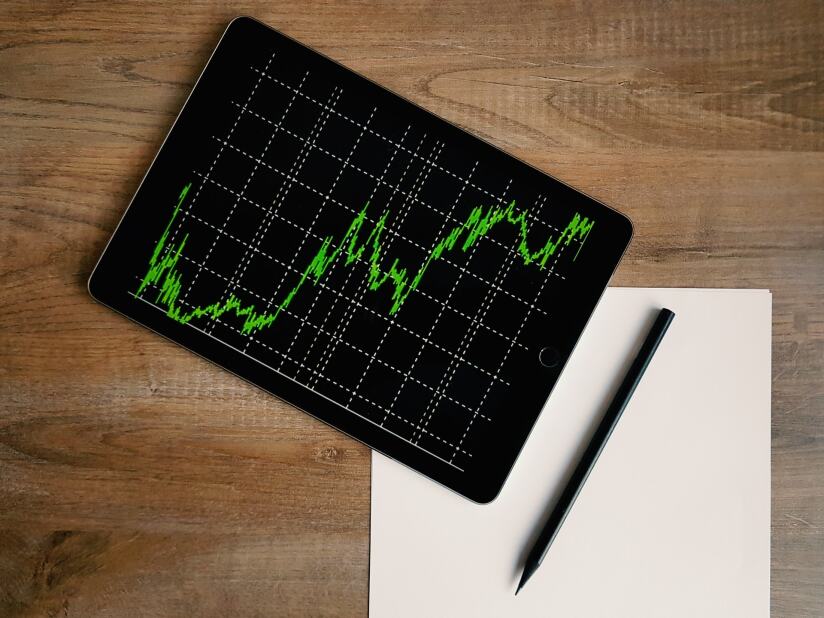 aerial view of a desk with blank paper, pen and tablet showing a line graph