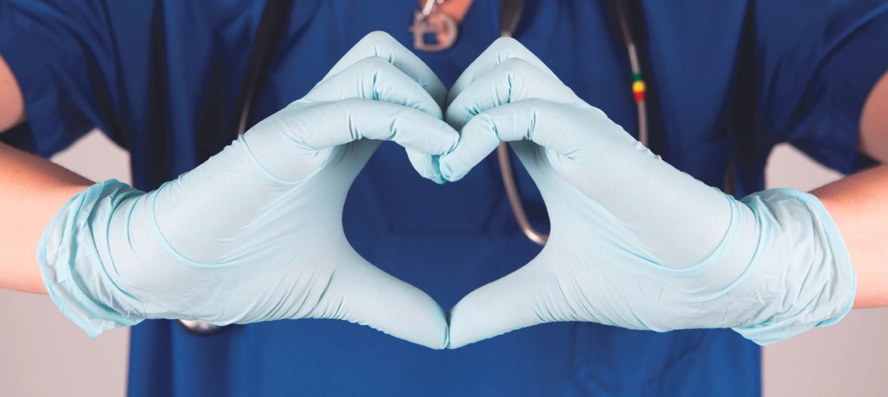 A doctor or nurse shpwing a heart with their hands