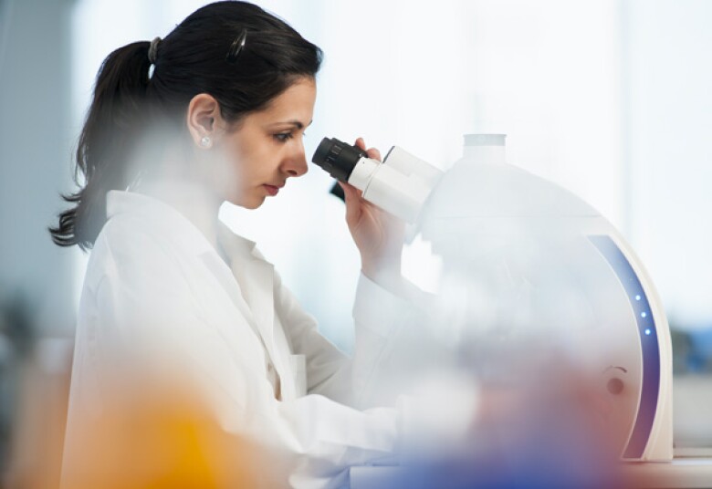 woman working in a lab looking through a microscope