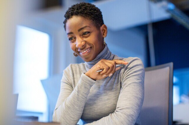 smiling woman sitting at her desk ready to take notes