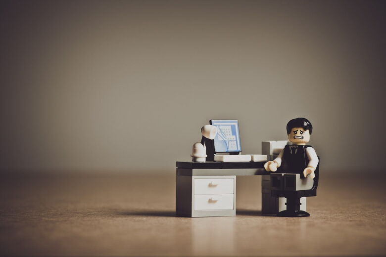 lego person with stressed face sitting at a lego desk