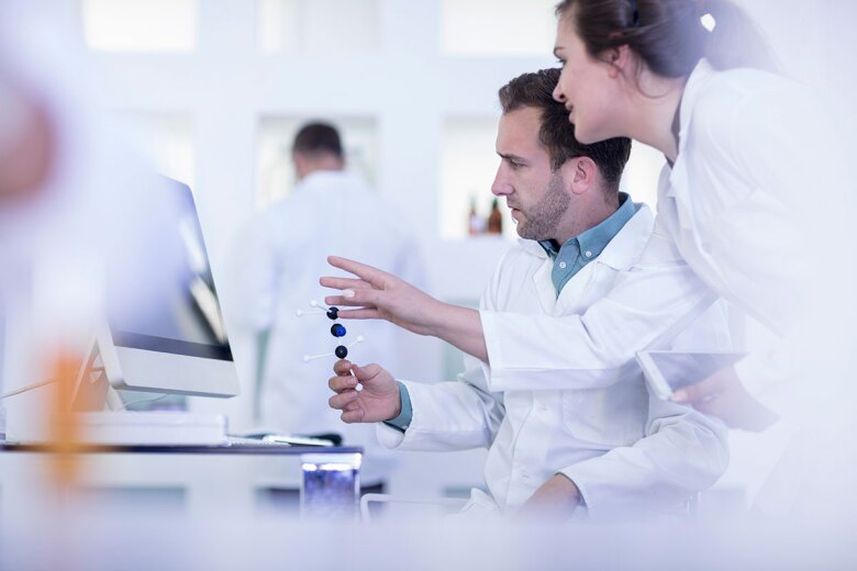 Laboratory workers looking at computer screen