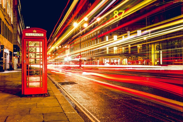 cars moving very fast past a red telephone booth
