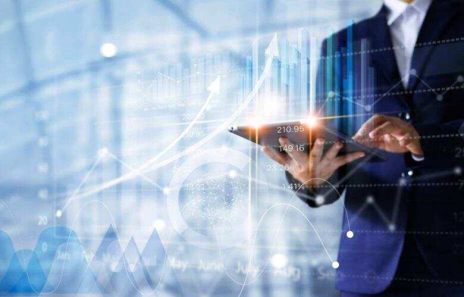 business man holding a tablet under a layer of various transparent graphs