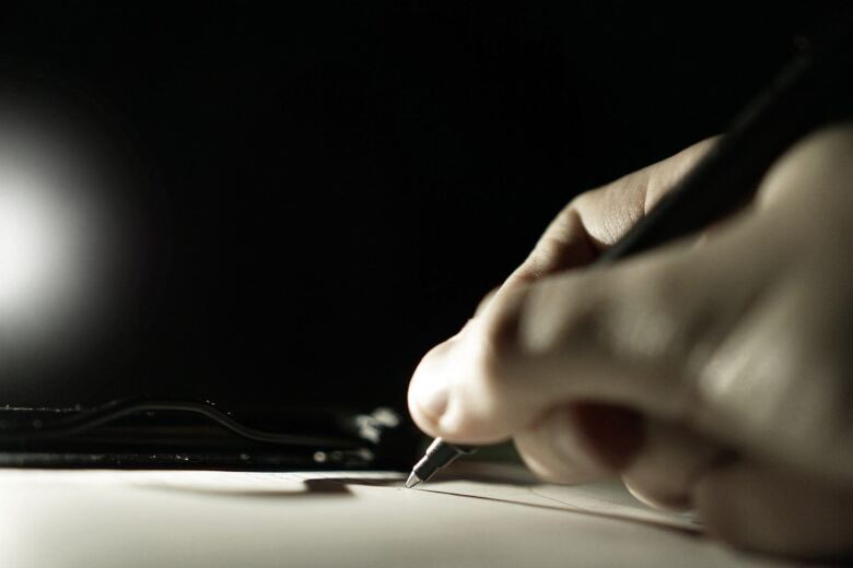 hand holding pen and writing on paper
